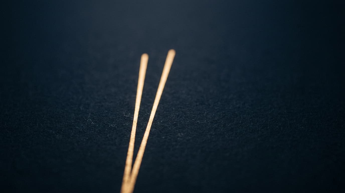 Abstract macro of a single clean upward line of warm light on a dark matte surface.