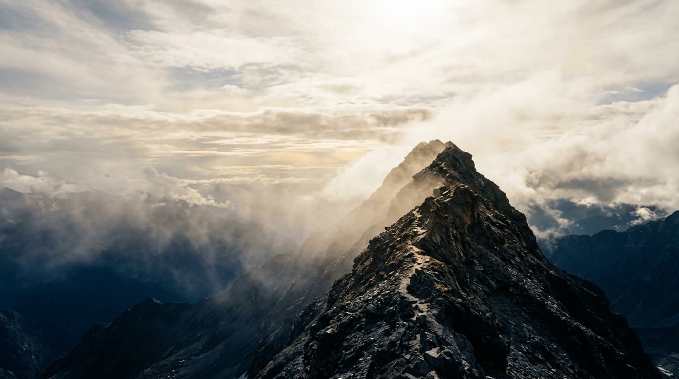 A figure-less ascending trail on a sunlit ridge, effort and progress.